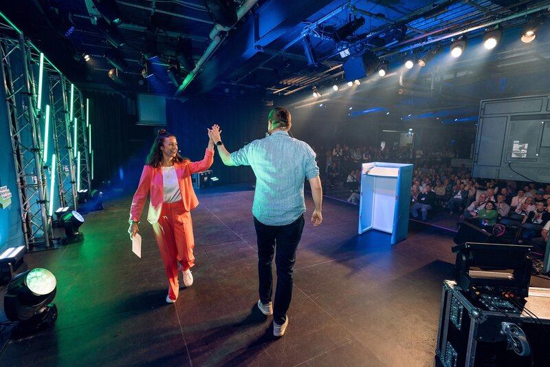 Moderatorin Hanna Zöller bei Event auf Bühne, High-Five mit Teilnehmer während der Premium Stage Experience