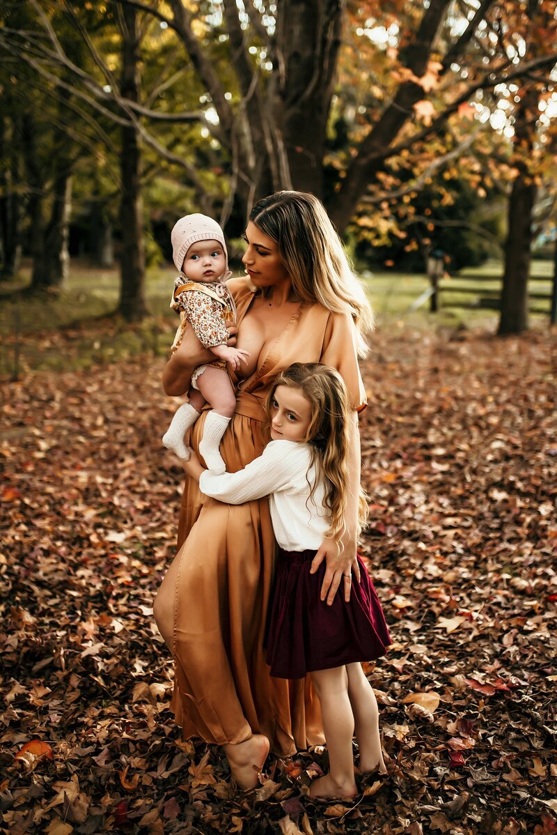 Mother holding 2 young daughters warm fall colors