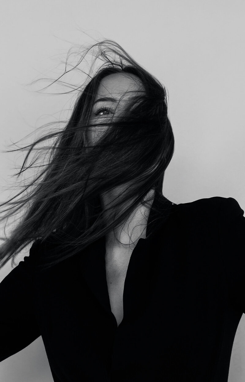 Woman with long hair across her face representing the confidence clients feel after getting luxury, natural-looking hair extensions.