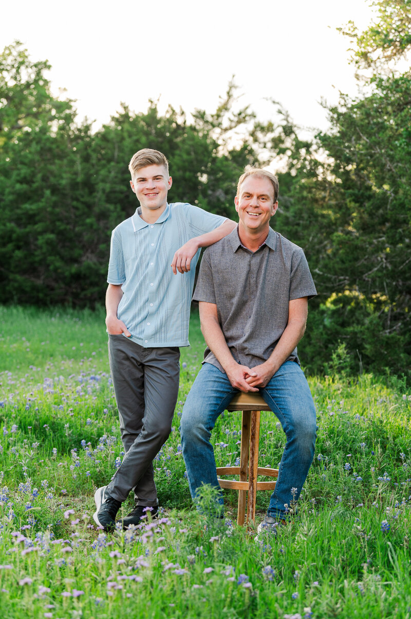 Father and Son laughing in a field  of Bluebonnets. Photographed by Lydia Teague Photography.