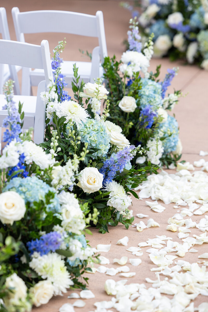 Spring wedding at WinMock at Kinderton, designed by Charming Carolina — white and blush petals scattered down the aisle between floral ground arrangements.