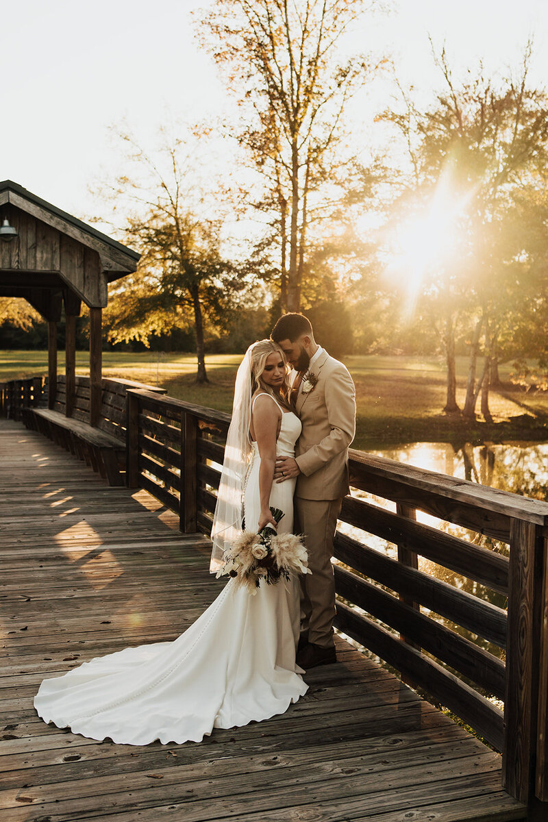 Georgia bride and groom share a moment on the dock of a lake at sunset