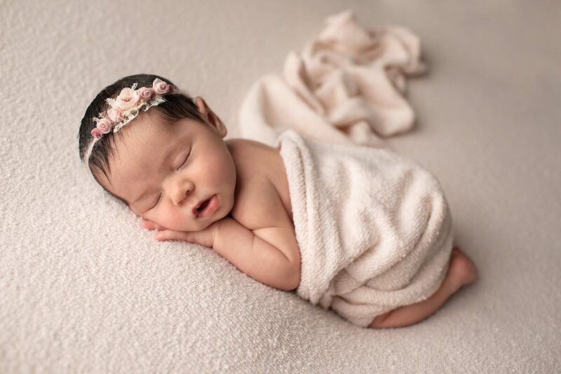 newborn girl wrapped in white fabric with a cream color headband by Baltimore Newborn Photographer
