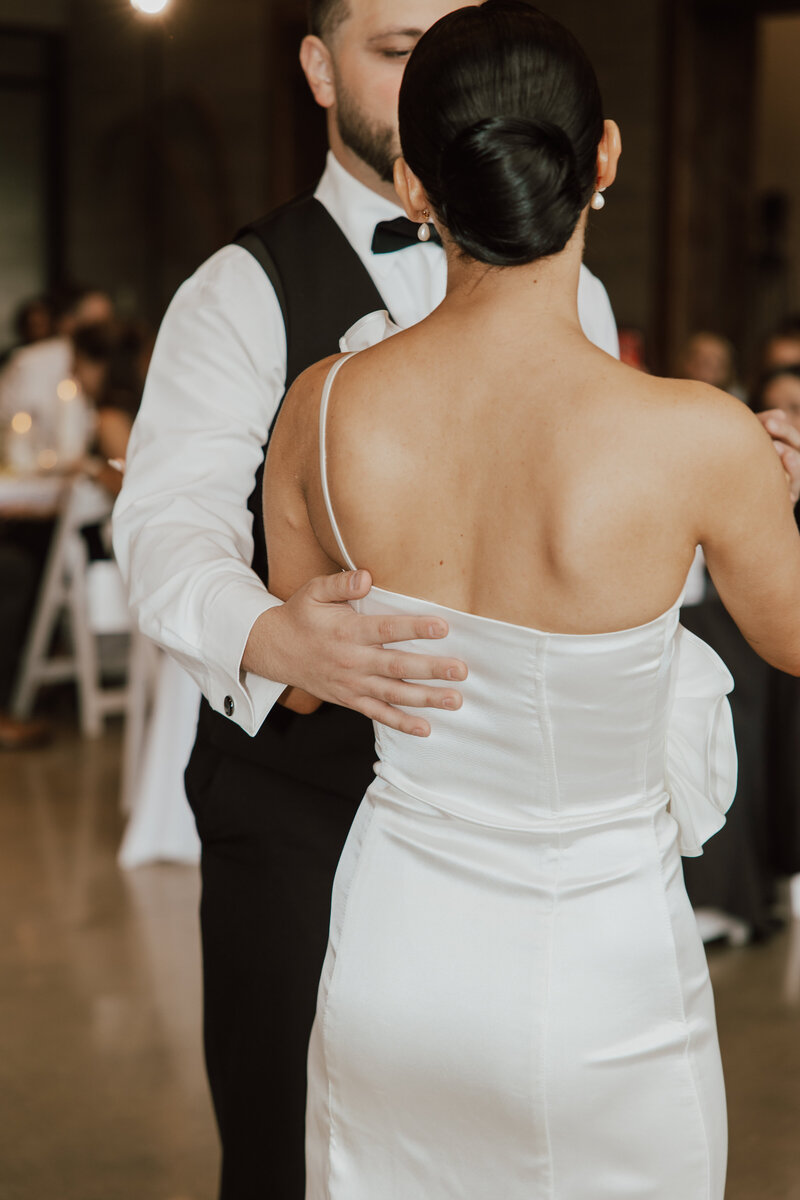 Bride and groom dancing getting a full look of the slick back bun done by promise bridal artistry.