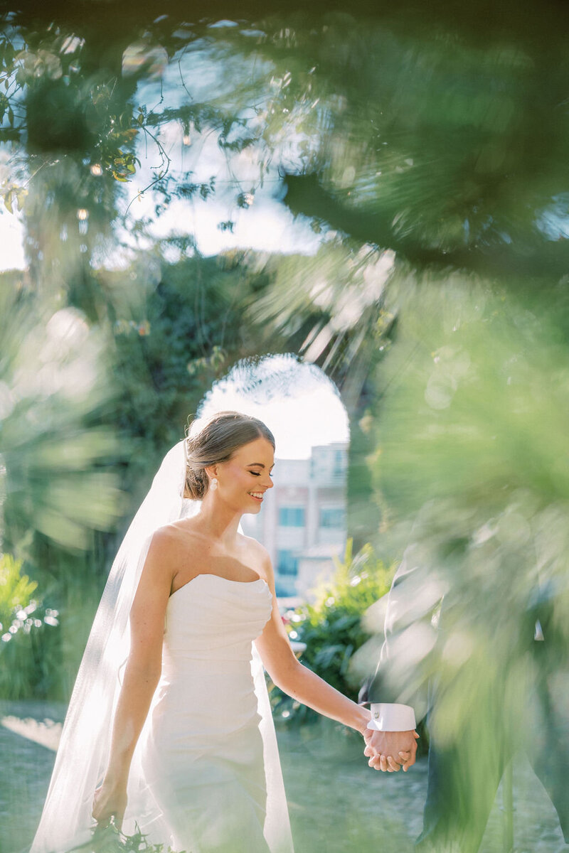 Bride walks through green leaves at Summerour Studio