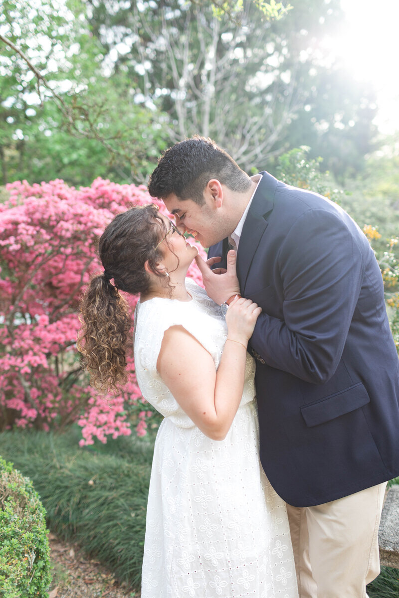Joyful engagement photo at Hills & Dales Estate with couple smiling in front of blooming azalea