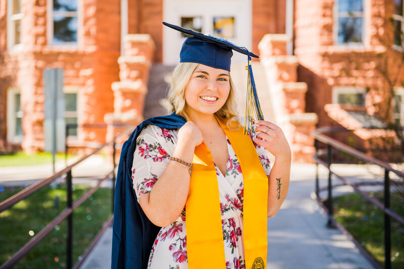 NAU senior graduation holding tassel and gown at Old Main at Northern Arizona University