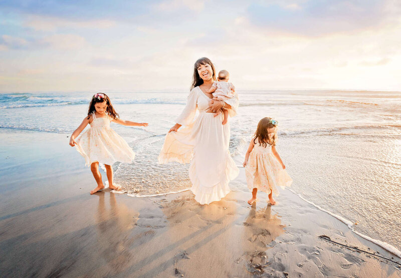 A mother playing the in the ocean with her children during their family photography session at the beach