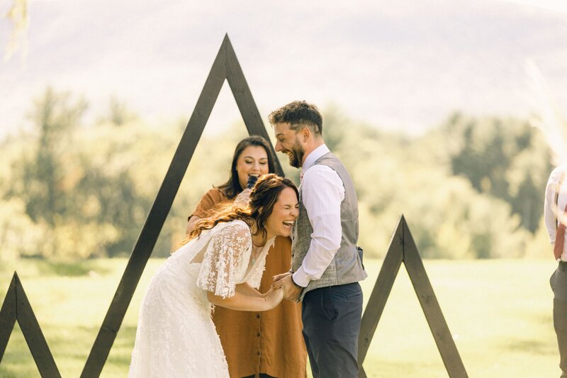 A bride looks to the right and smiles in her wedding gown as her bridesmaids as her walking past her.