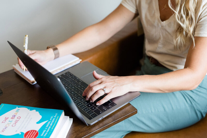 Amy sitting in her office chair typing on her Mac