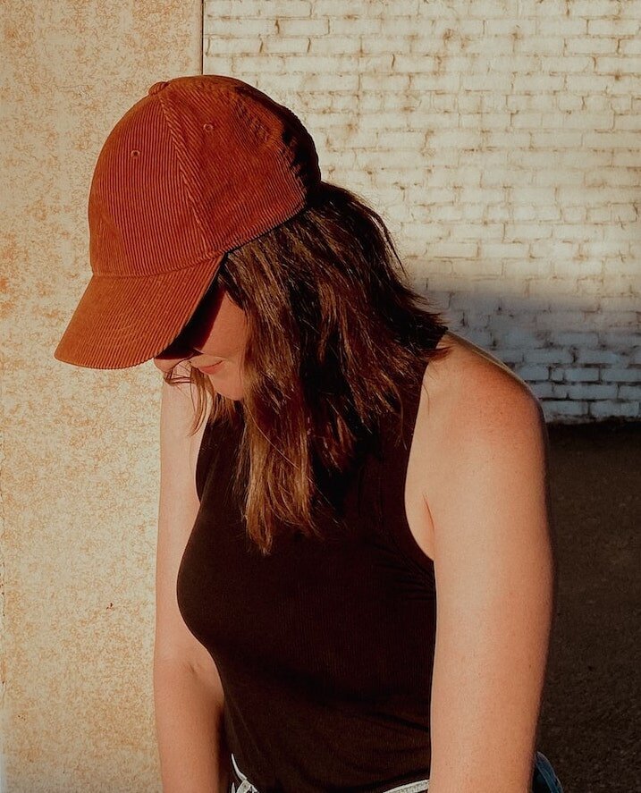 website designer lorin husa is wearing a thrifted brown baseball cap, black tank top and levi's jeans