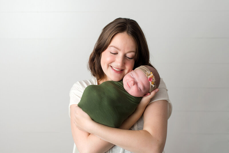 Mom snuggling new baby boy during family portrait.