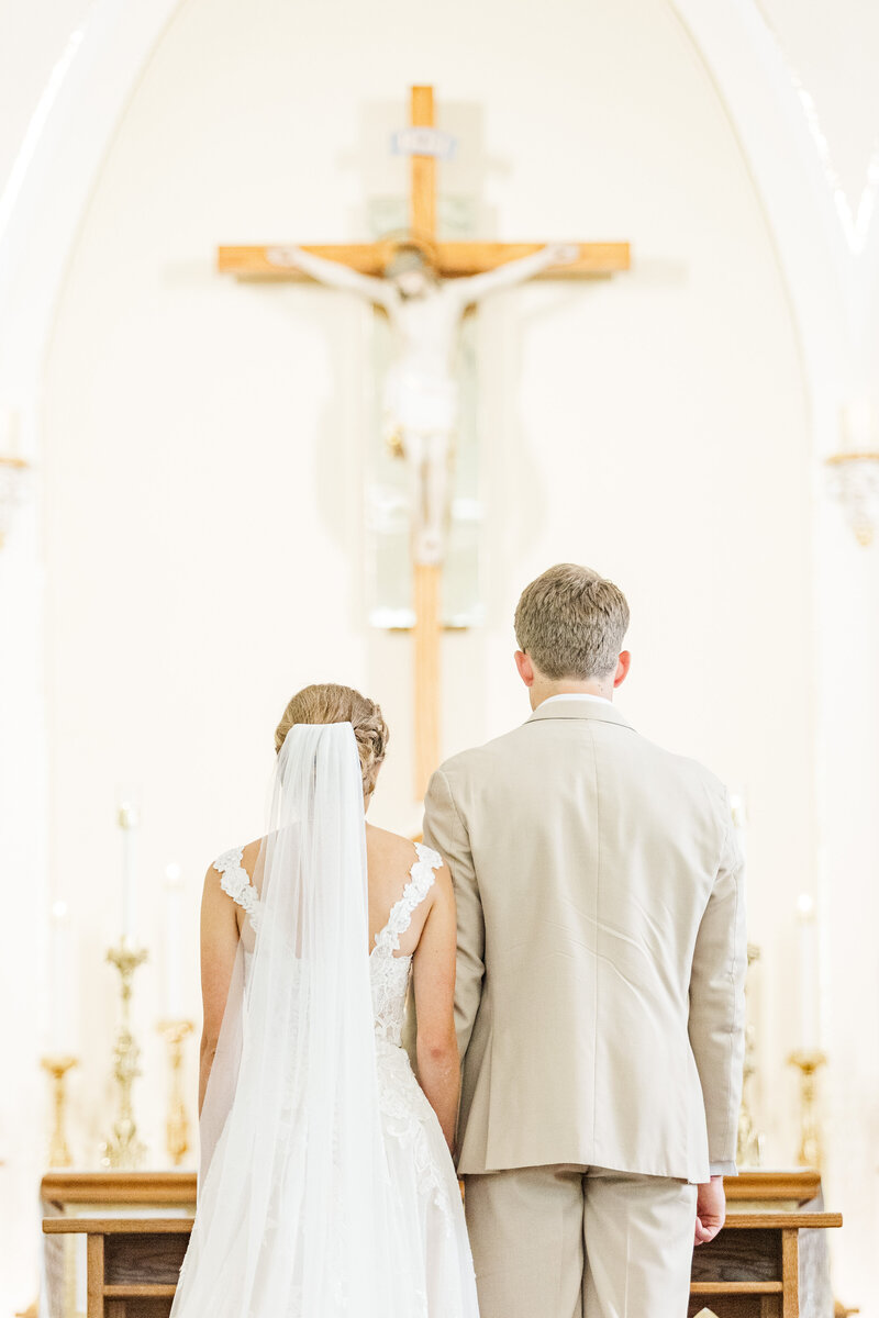 bride and groom praying together in a Catholic church on their wedding day