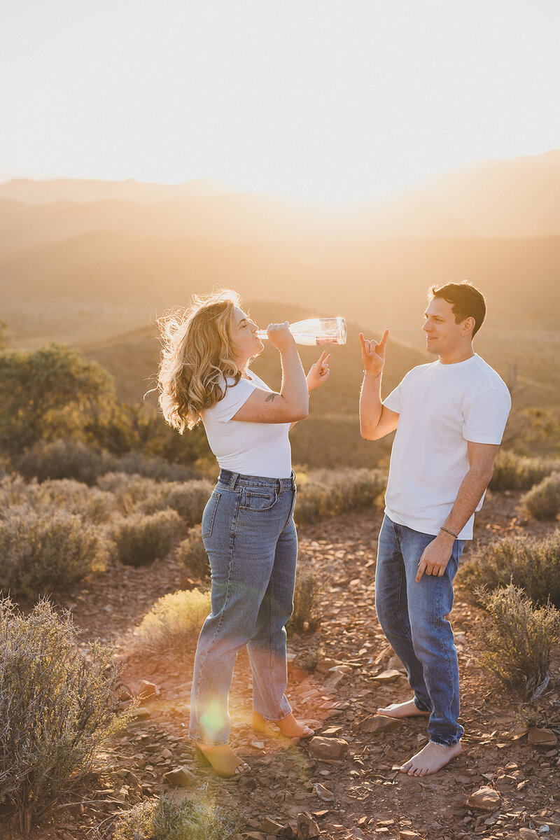 couple drinks champaign in desert during las vegas engagement photo session