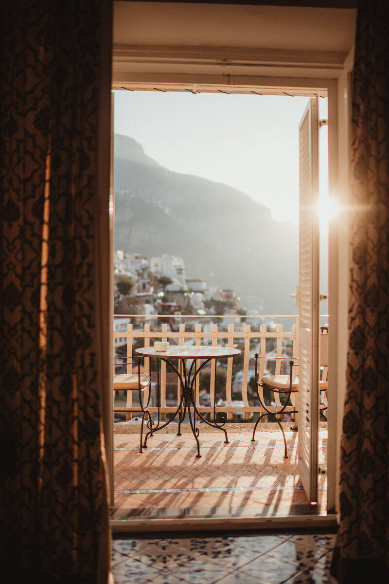 a hotel balcony with a bistro table in the frame and the sun setting 