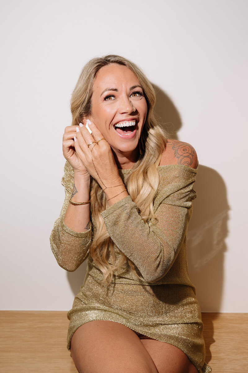 A woman life coach in a gold dress crouching down