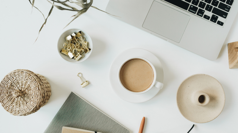 coffee on a desk with gold paperclips and an opened laptop