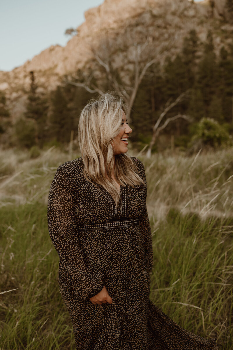 Denver photographer poses for photo while walking in a field of greass
