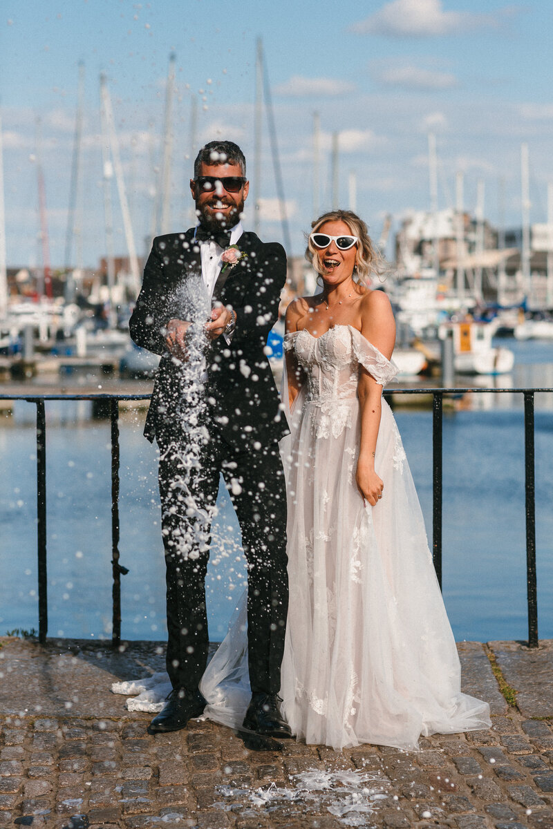 Couple spray champagne at  their Barbican based wedding day in Plymouth