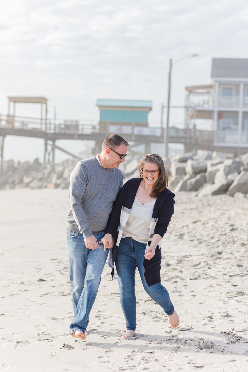 Amanda walks along the beach, bumping hips with her husband Craig