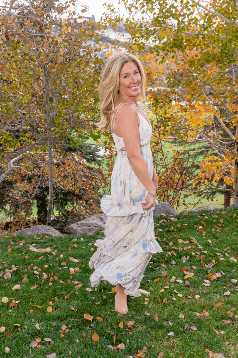 author Karla Olson in a dress in front of autumn trees