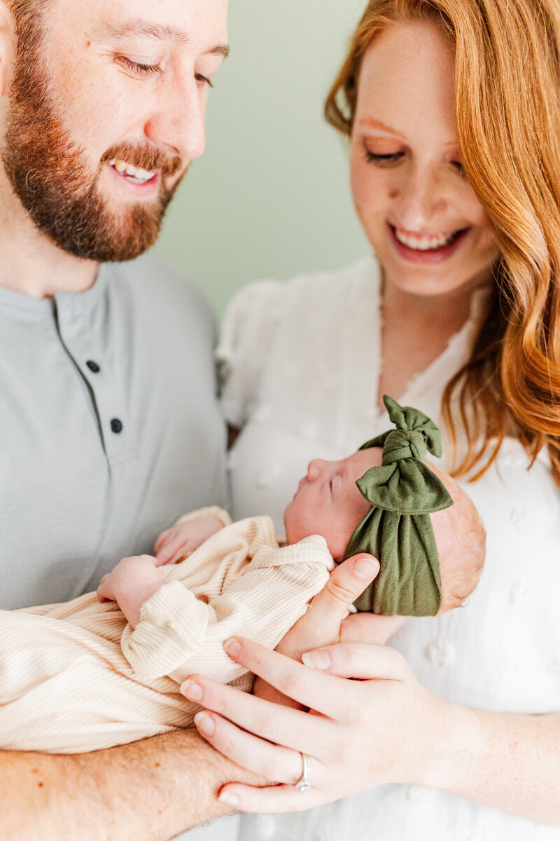 parents smiling as they hold their newborn baby