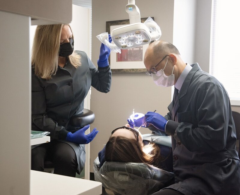 Raymond J Kao, DMD doing a dental check up on patient with dental assistant in Kao Dental office