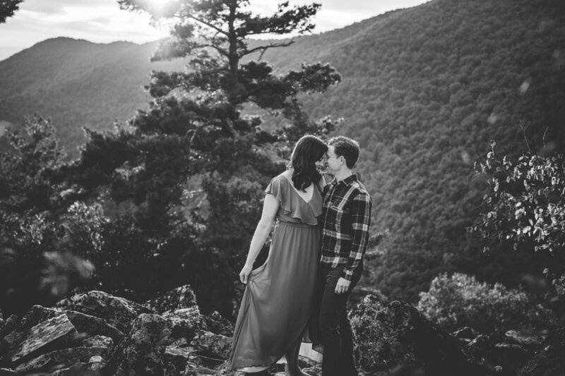 black and white image of a man and woman cuddling on a mountaintop