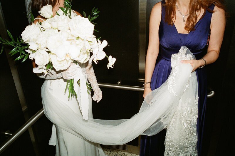 bride with bridemaid holding dress by film wedding photographer Noble Photo Co