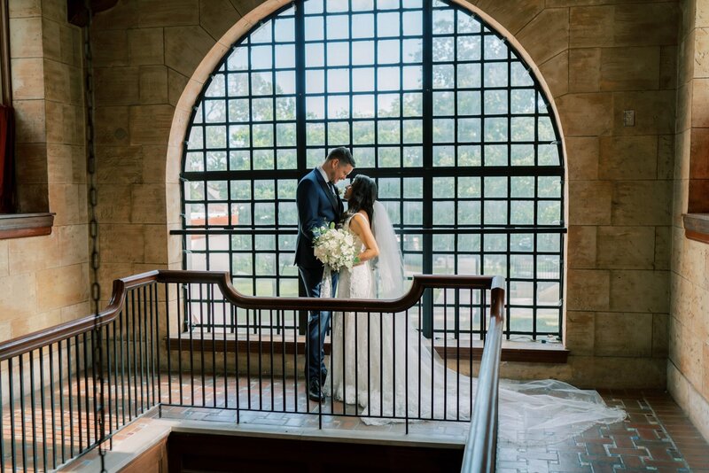 A bride and groom stare into each other's eyes while in front of a large glass window