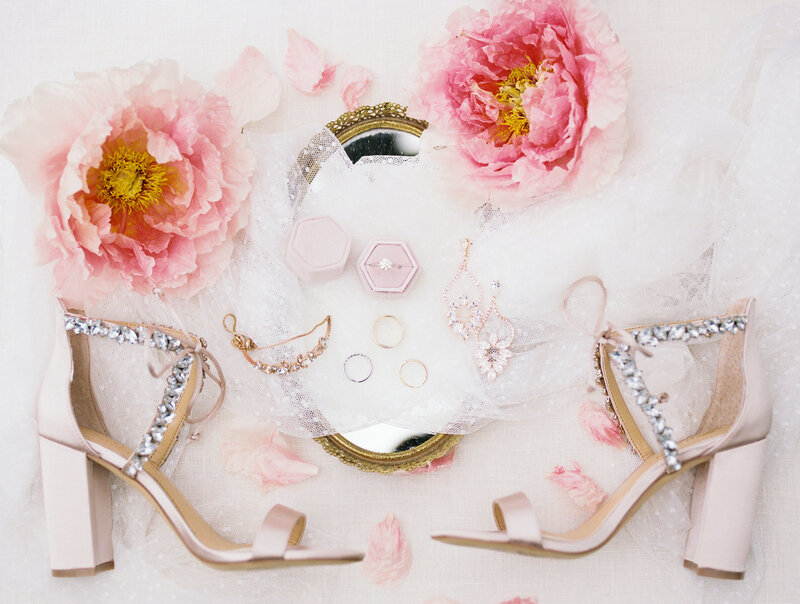 Display of peonies, jewelry and pink high heel shoes on a flatlay
