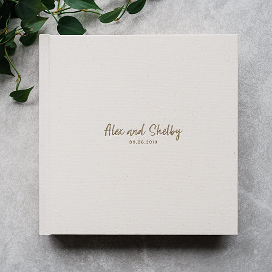 A cream-colored wedding album with gold debossing