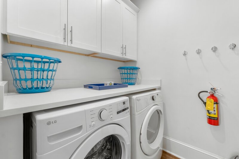 Bright laundry room with LG washer and Whirlpool dryer, custom cabinetry, and counter space at Panama City Beach vacation home.
