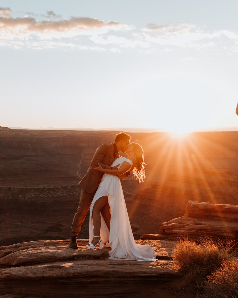 bride and groom dip kiss at sunset