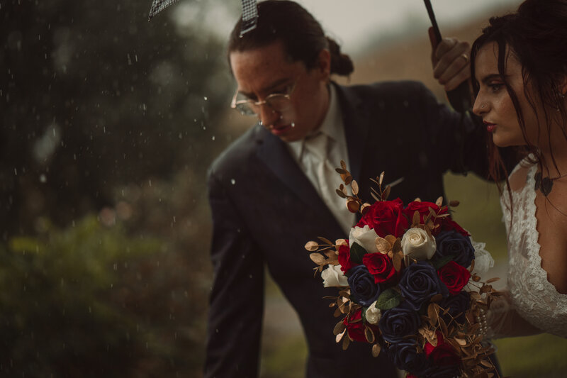 Wedding couple run through the rain after their ceremony with bouquet in hand.