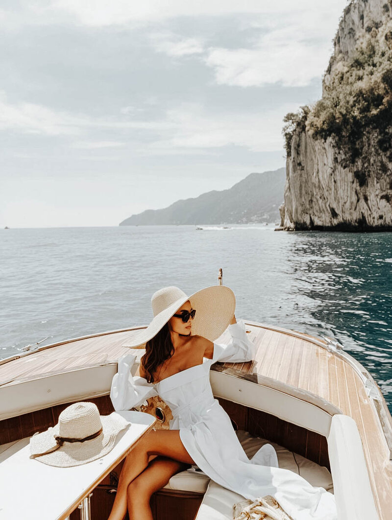 Traveler relaxing on private boat tour exploring coastal cliffs and secluded waters. Tailored Oasis Travel Co.