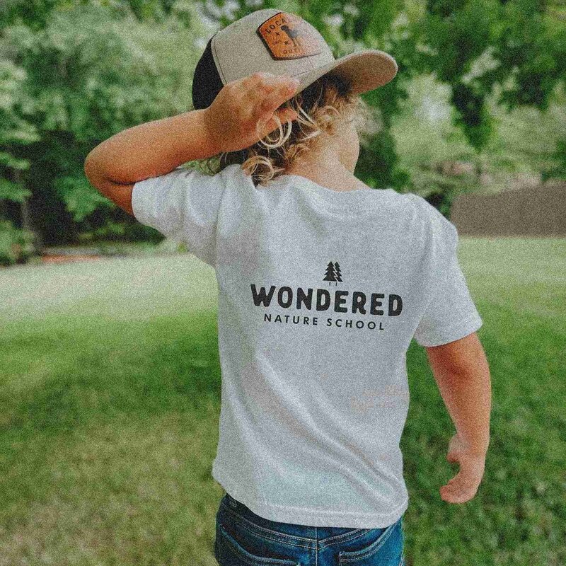A peschool boy wearing a hat and a "Wonderland School" shirt, representing the fun and learning at Wondered Nature School.