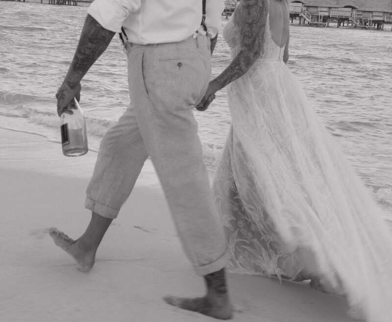 A stunning luxury wedding in Bora Bora, where the couple walks hand in hand along the crystal-clear shoreline, framed by lush palm trees and ocean views.