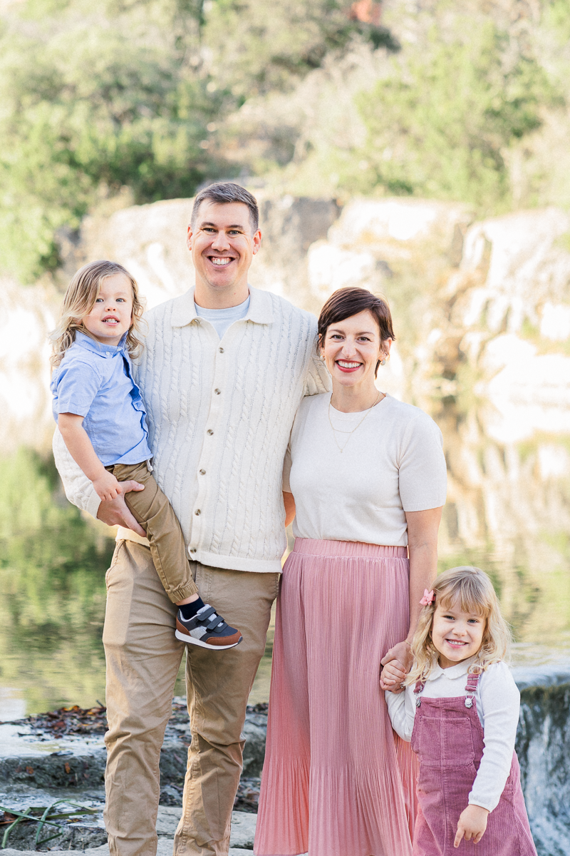 a family of 4 stands in front of the San Gabriel river at Blue Hole park.