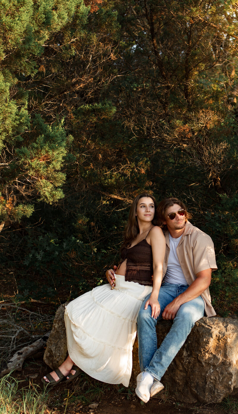 couple sitting on a rock during golden hour looking off in the distance.