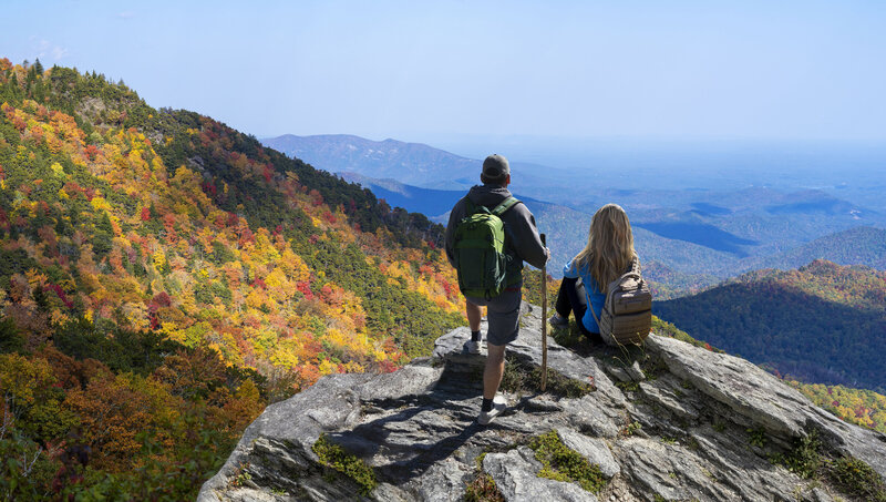 Hikers on rocks looking at view while they visit Asheville