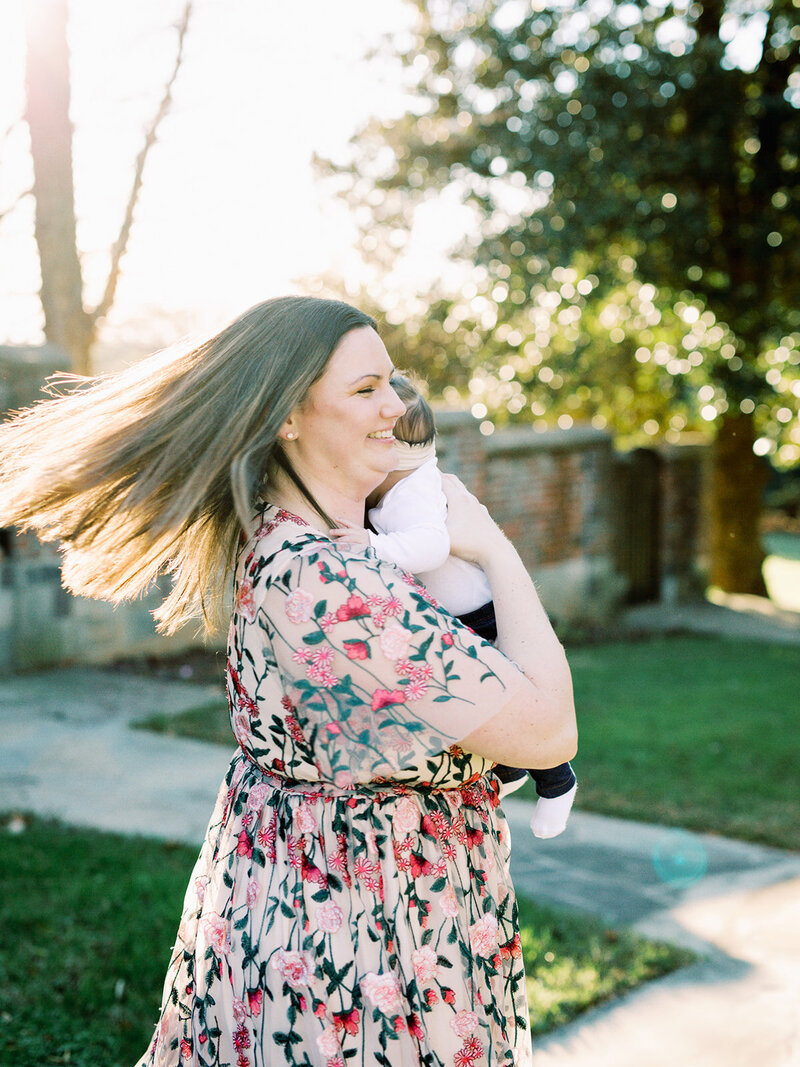 A mother smiling while holding her baby by Katie Stansfield Photography, a Richmond family photographer.