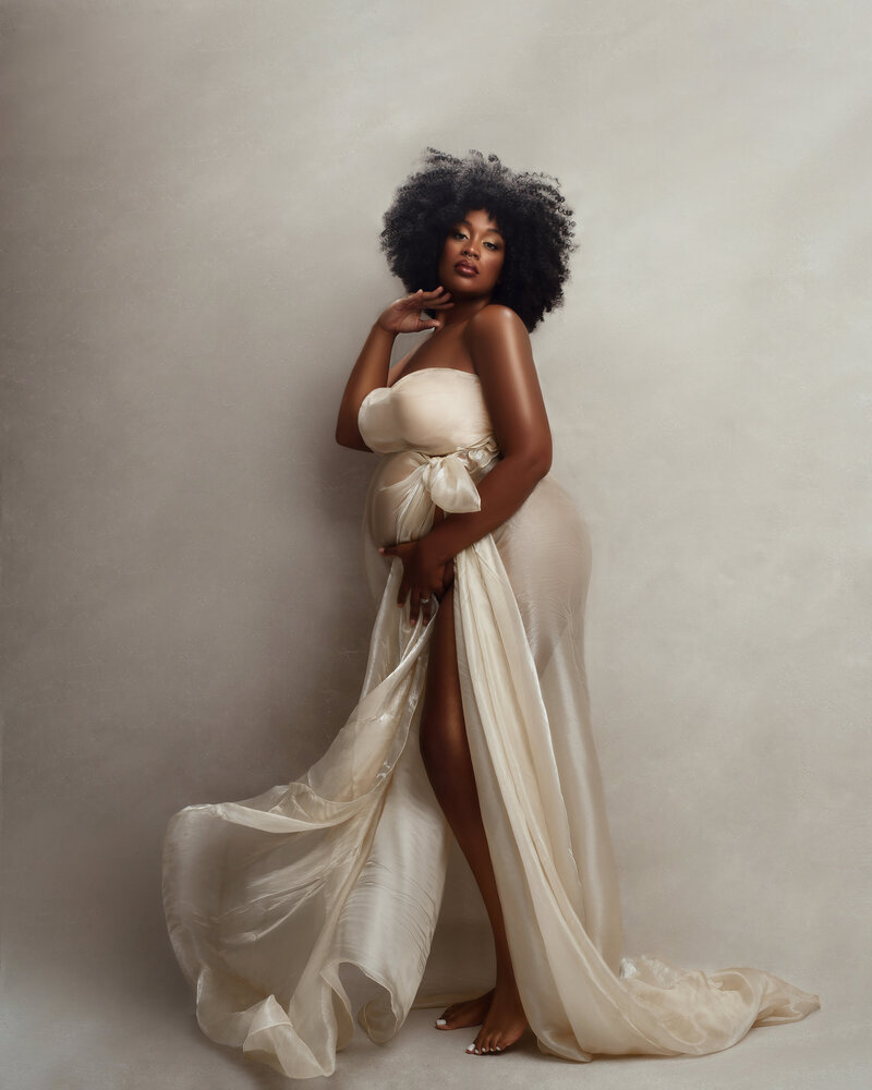 Fine art, classic, fabric, maternity poses, Elegant maternity portrait in flowing neutral gown, softly lit by natural window light