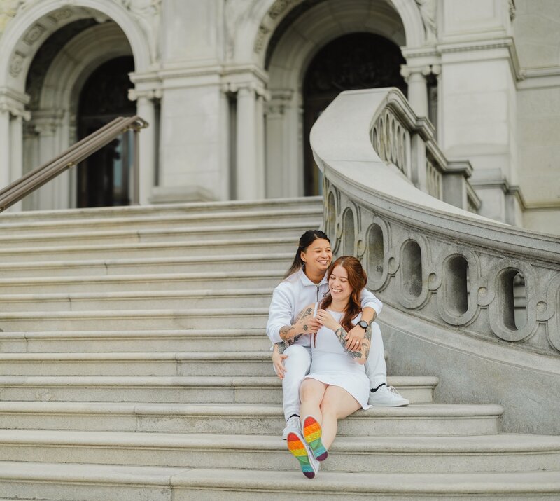 A couple sitting on an outdoor staircase with their arms around each other 