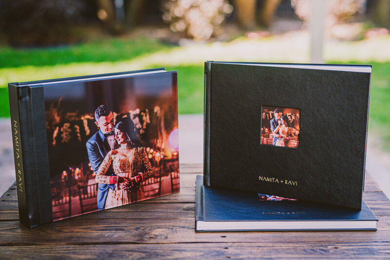 An large flushmount wedding album with an acrylic cover along with two smaller photo books sitting on a wooden table