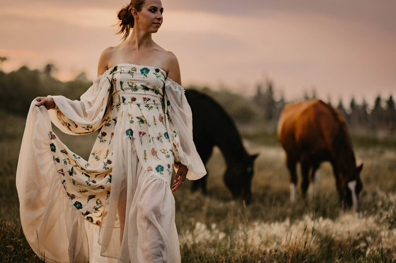 women in a dress in a field of horses during an empowerment photo session in southern Saskatchewan. 