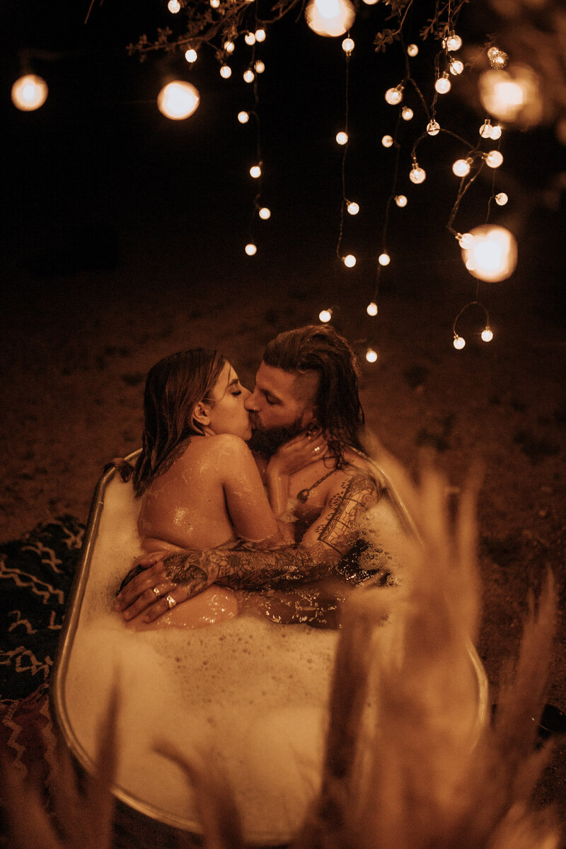 tattooed long hair man kisses his wife in a bubble bath steamy session