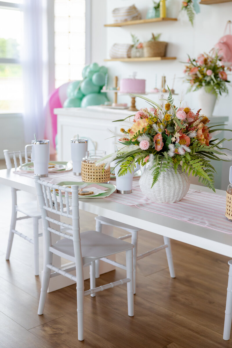 White table and chairs for kids with beach flowers, candles, and sunglasses cookies.