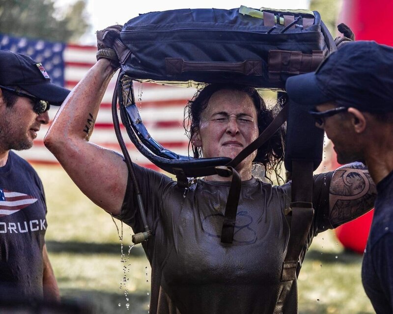 The Bakery athlete completing GORUCK Selection with ruck bag overhead, showcasing endurance and resilience. 
