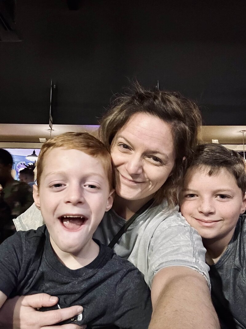 Melissa, the Middle GA family photographer behind Fire Family Photography, in a candid moment with her two sons. All three are laughing and embracing, showing the authentic, joyful connection she values capturing for other families. A glimpse into her own 'beautifully messy story' that informs her photography approach.